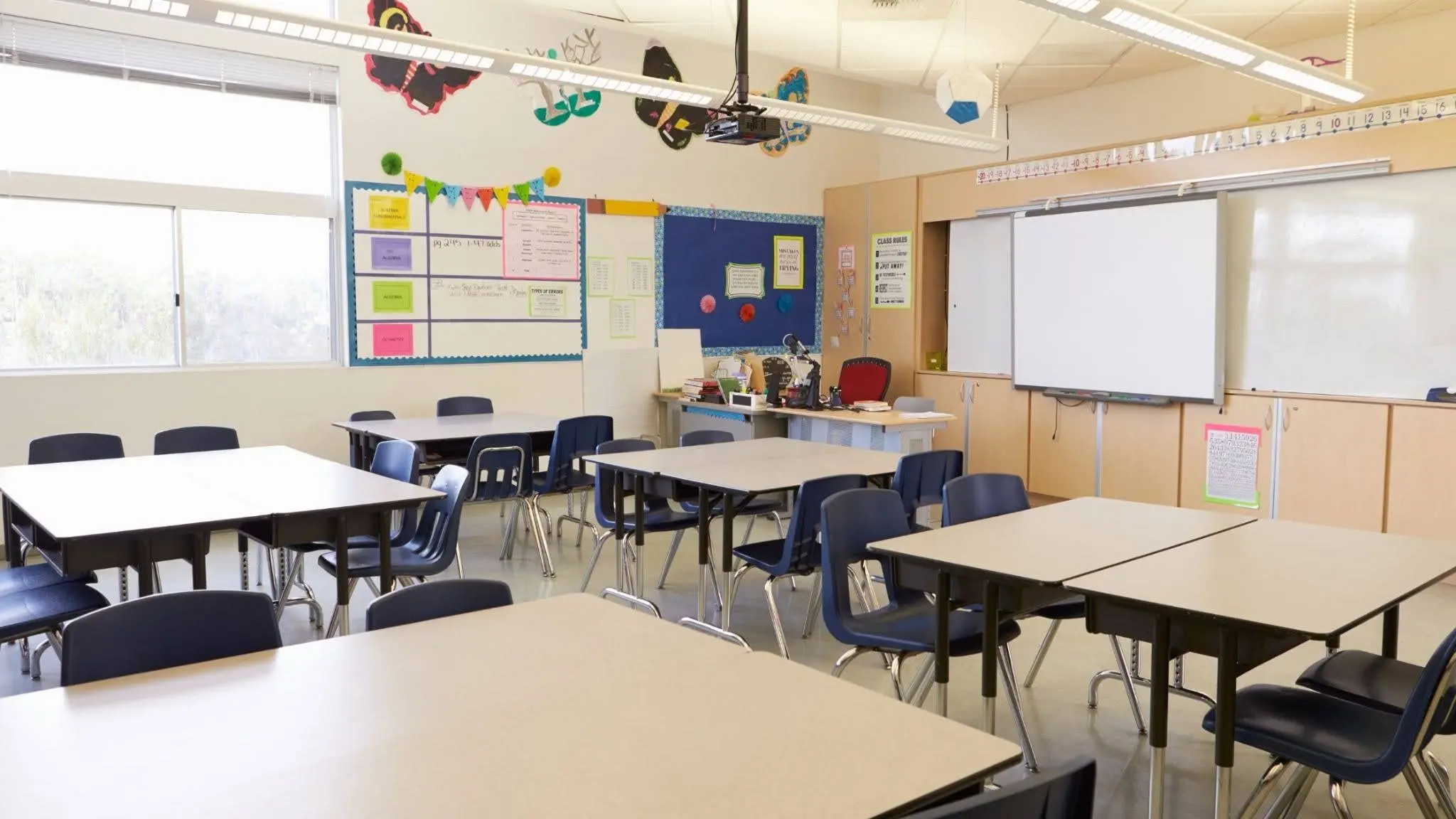 Bright classroom with tables, chairs, and educational displays in a child care center.