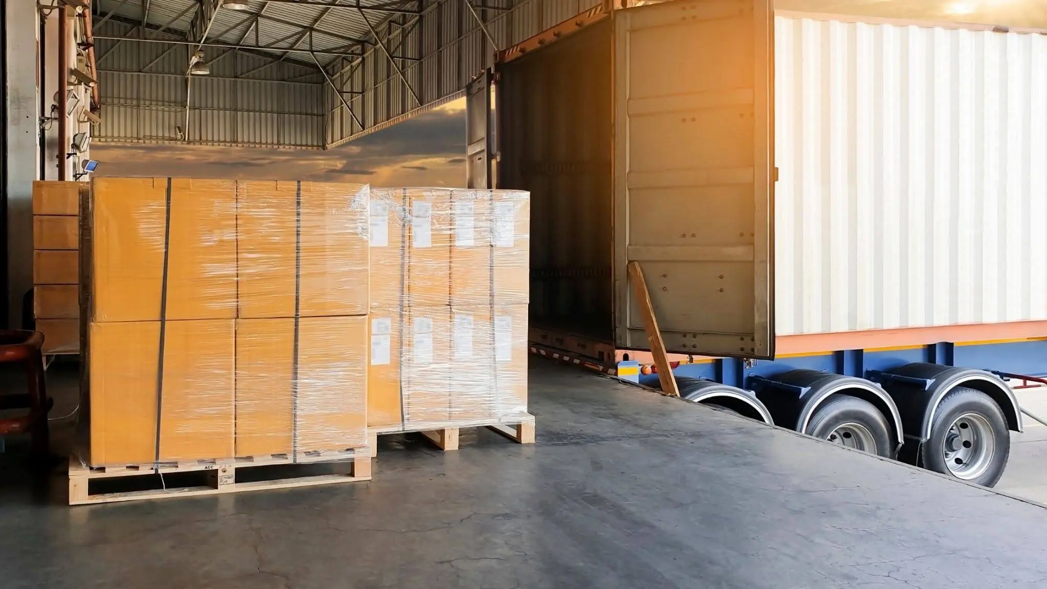 Loading dock with pallets of boxed goods and a delivery truck.